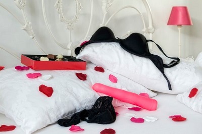 black bra and black panties and pink dildo on pillow 